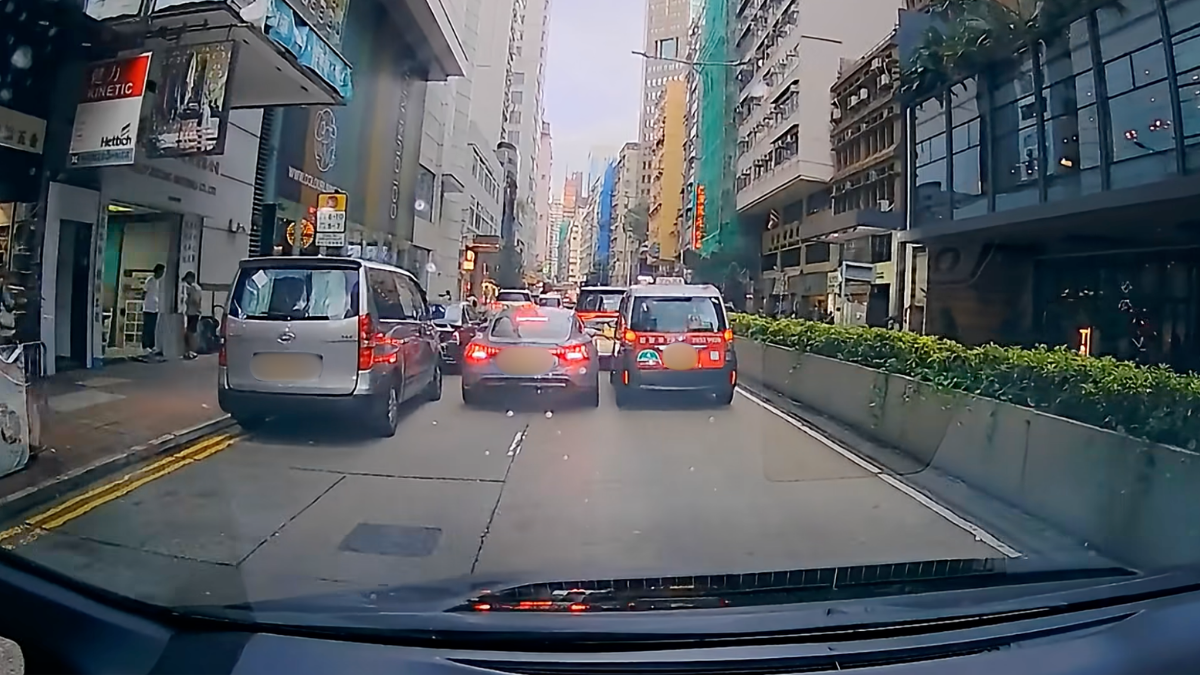 兩車互不相讓慢駛僵持近10秒，詎料私家車司機絞低車窗，突然伸手將的士左邊車門打開，趁的士司機停車關門、與前車拉開距離之際，立即切往右線，最終得逞。