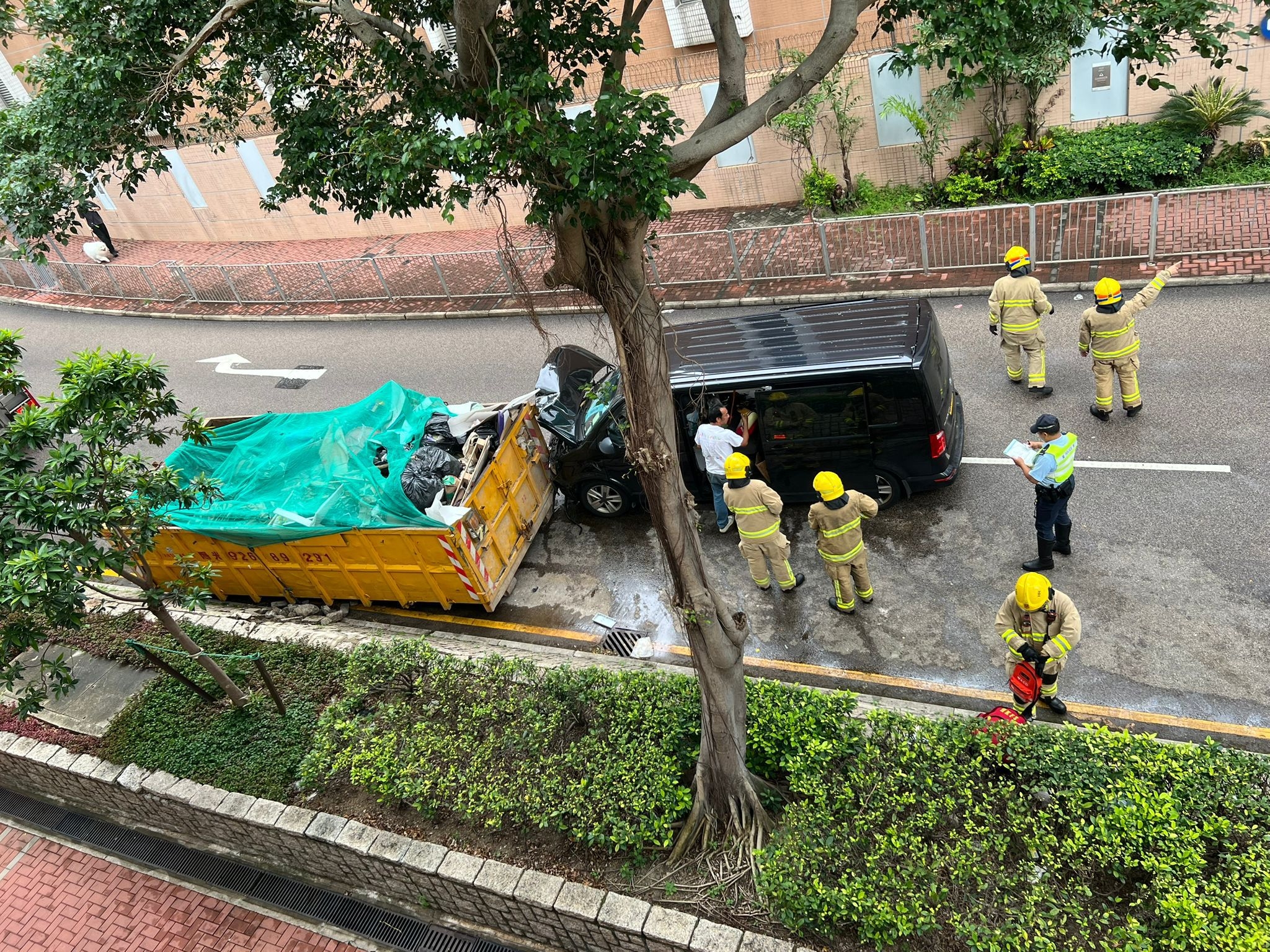 涉事客貨車車頭冚撞至摺起並凹陷，而花槽受損面積則約為1米乘1米，消防與警方在場調查。（Facebook圖片／香港交通及突發事故報料區／Muntimg Po Po）