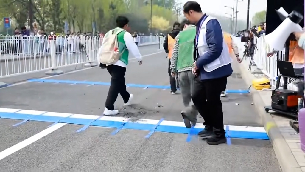 工作人員到場將機械人抬上擔架，並將散落在地上的零件也一併拾起，之後迅速離場。（網上影片截圖）