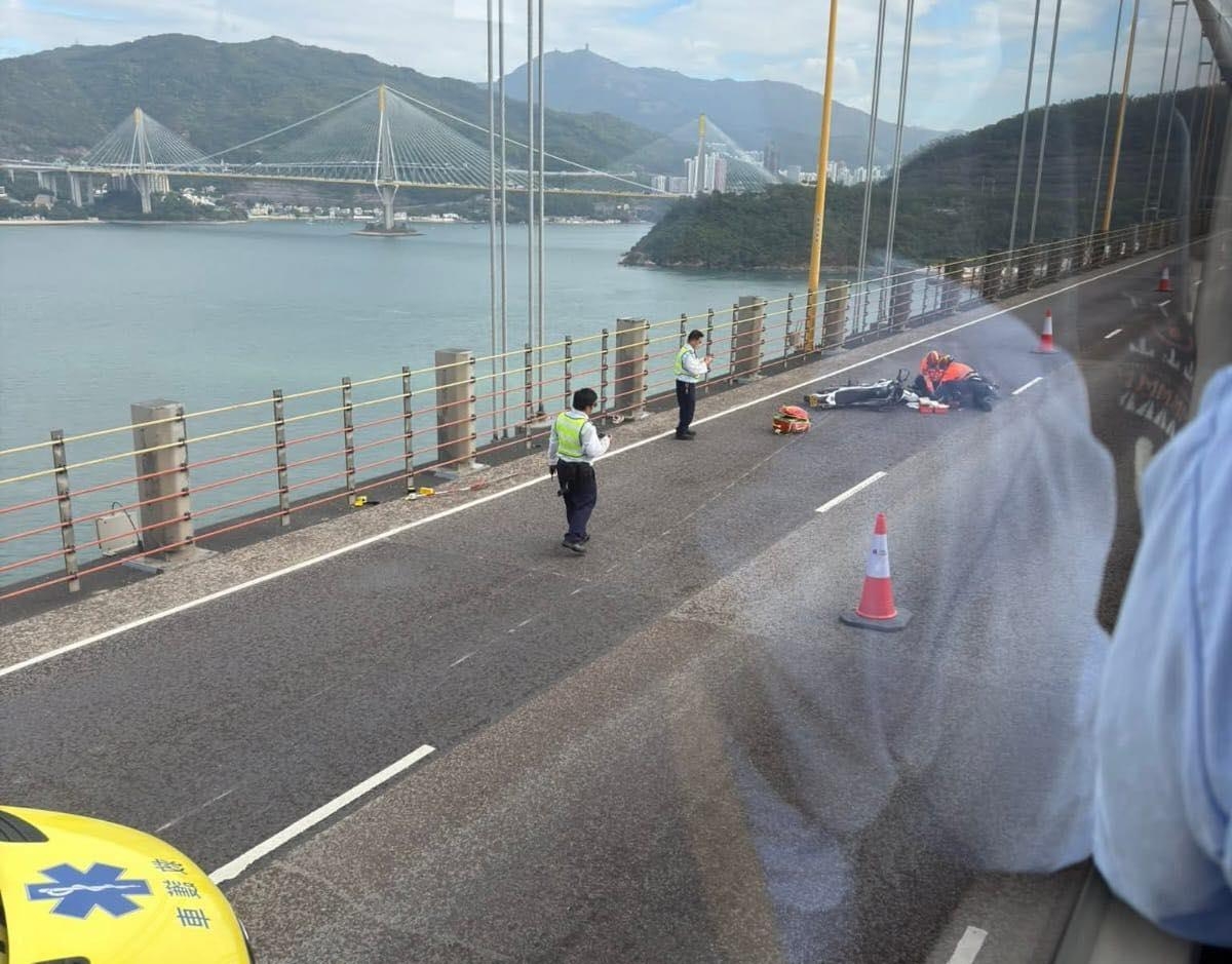 從現場圖片可見，電單車倒在慢線，旁邊放置交通錐，已有人員在場處理，背景可見青馬大橋及汀九橋景觀。