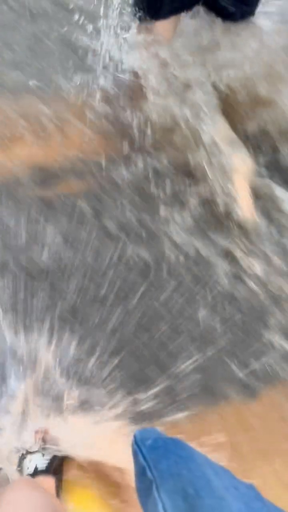 港女穿著拖鞋，在「激流」中涉水而行，水位淹蓋腳踝，要步步為營地走過馬路。