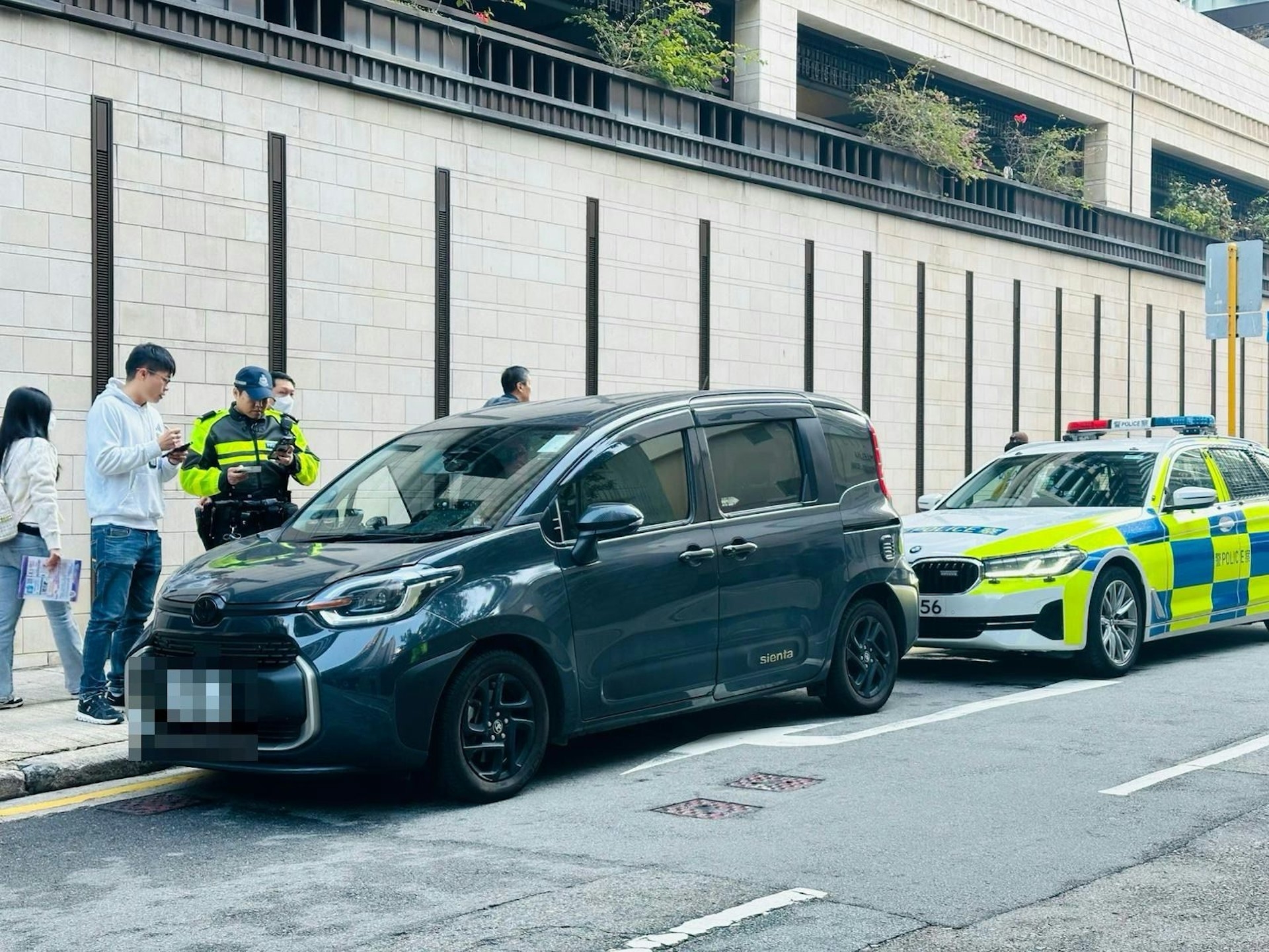 警方於灣仔打擊「白牌車」，喬裝乘客「放蛇」搭車，並拘捕兩名男司機，涉嫌「利用汽車作非法出租或取酬載客用途」。（警方圖片）