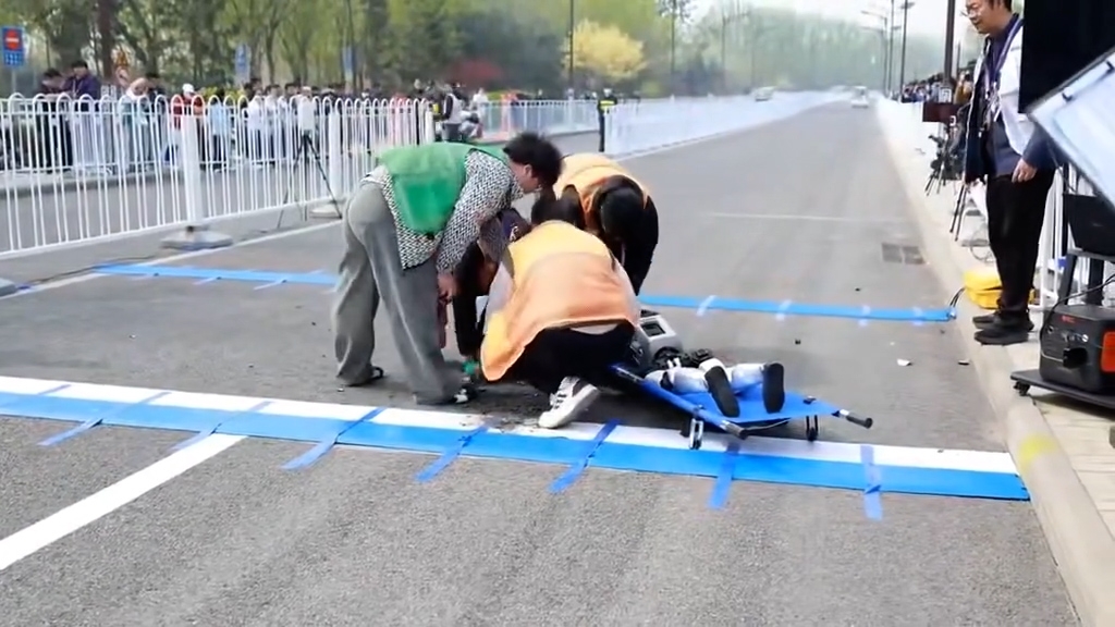 工作人員到場將機械人抬上擔架，並將散落在地上的零件也一併拾起，之後迅速離場。（網上影片截圖）