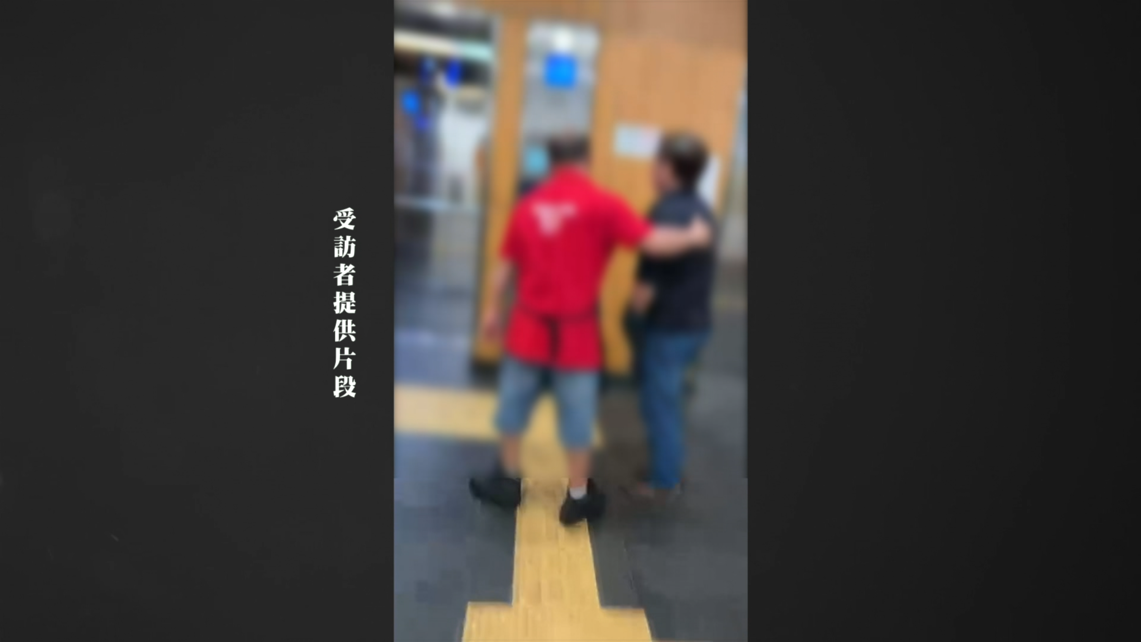 一名穿紅色制服的職員拉著吸煙男往電梯方向離開，試圖平息事件。