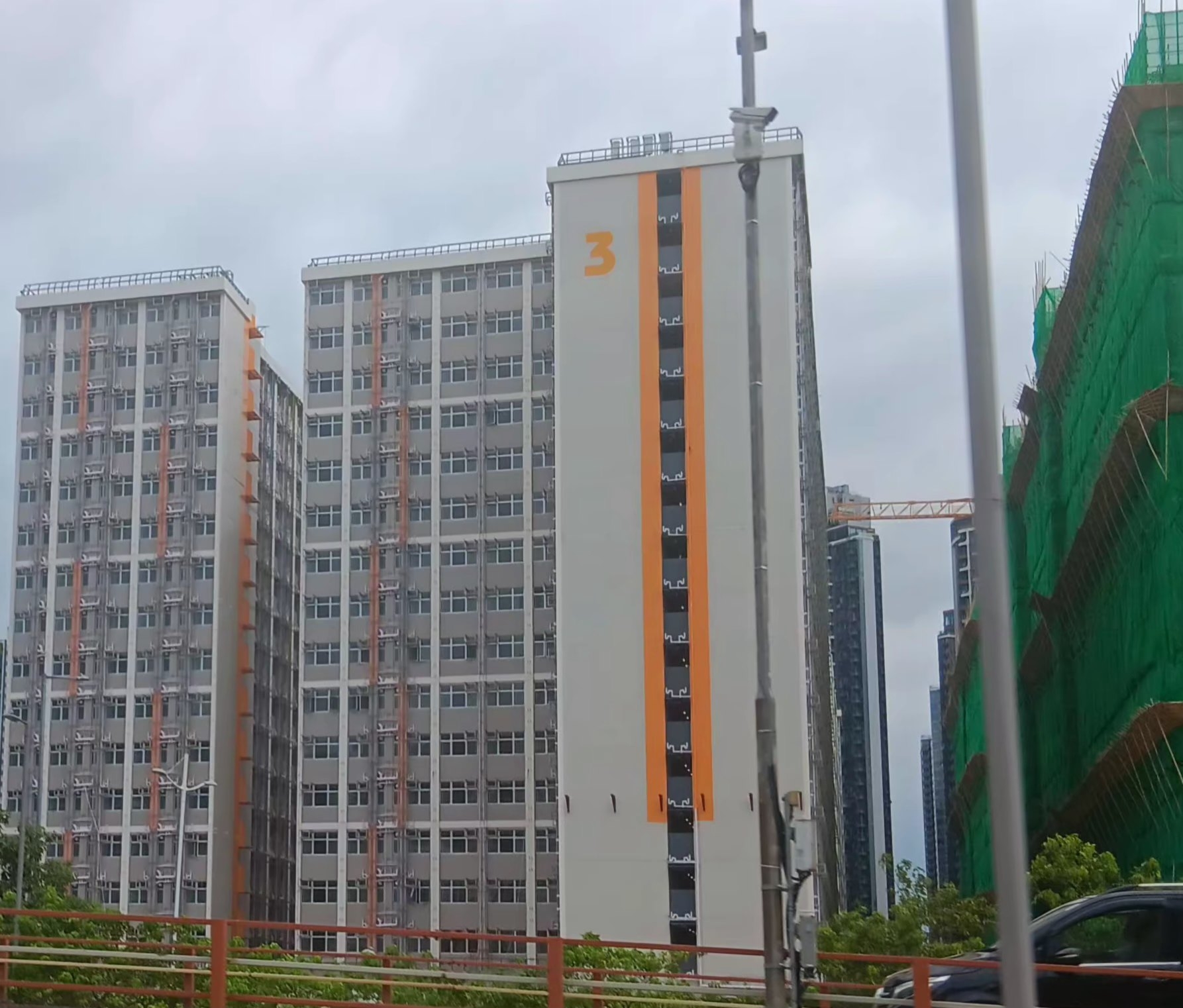 從相片可見，啟德簡約公屋採用灰白及橙色作主色，外形四四方方，樓層、窗戶排序整齊，以數字作為大廈座號，相關設計與後方大廈形成強烈對比。（Facebook圖片／慈雲山資訊交流／Pollyin Fu）