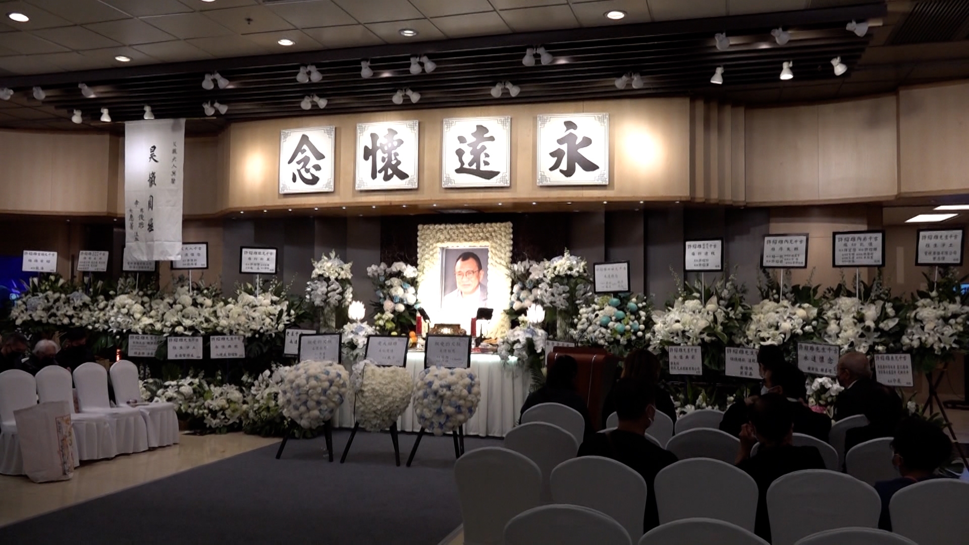 今日是Benz哥舉行設靈的日子，靈堂內一片花海，不少生前好友紛紛送上花牌，包括周潤發、乾女兒佘詩曼、林峯、成龍、古天樂、鄭裕玲、宣萱等。 