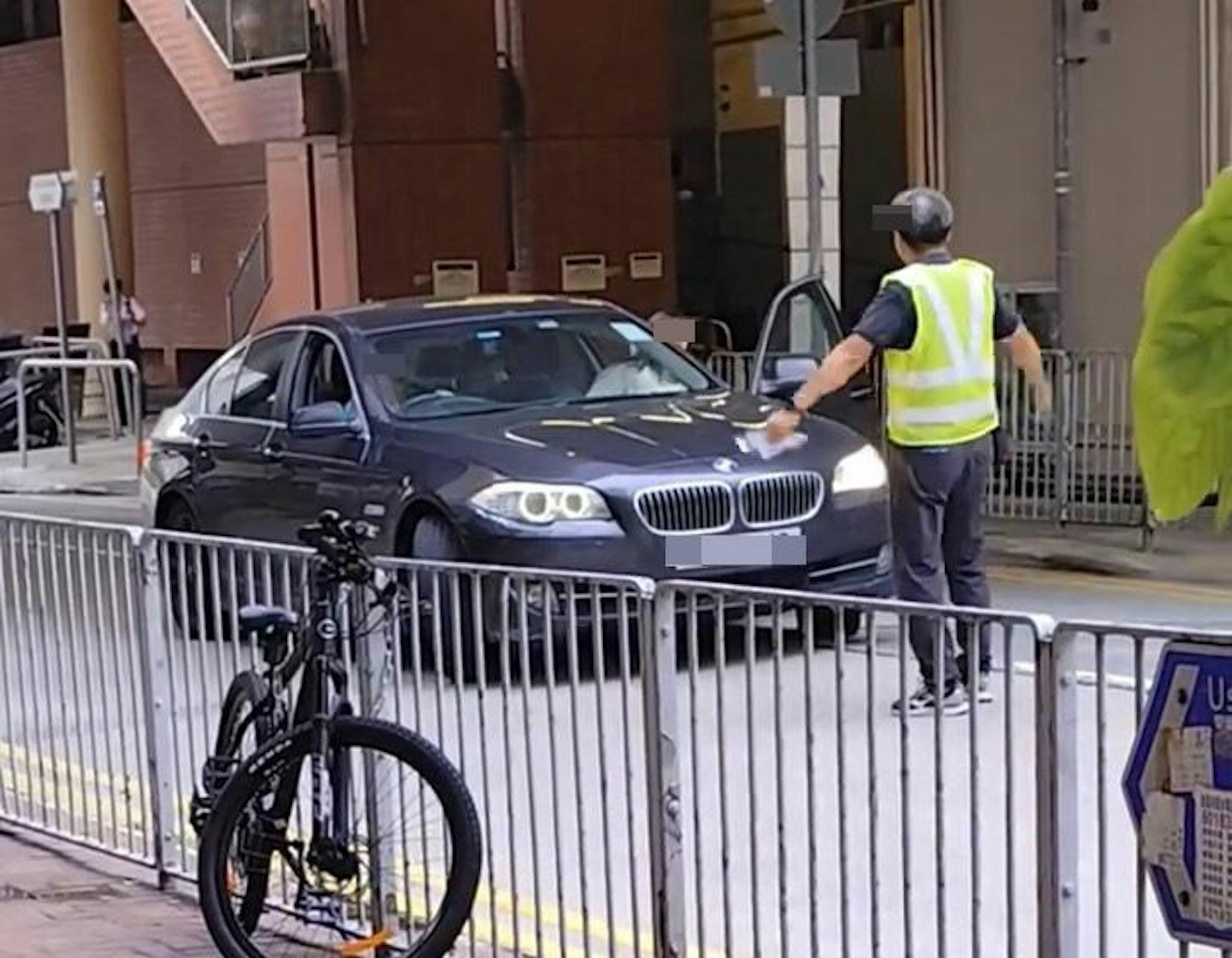 男司機縮回車內後，坐在副駕駛座的女乘客接力打開車門，與保安爭論。
