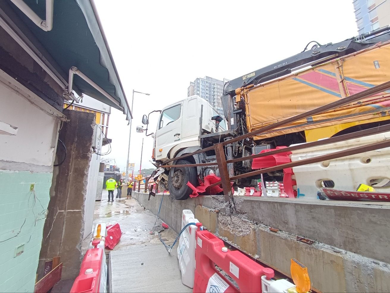 元朗吊臂車疑天雨路滑失控，撞欄及水馬更險衝入村屋。