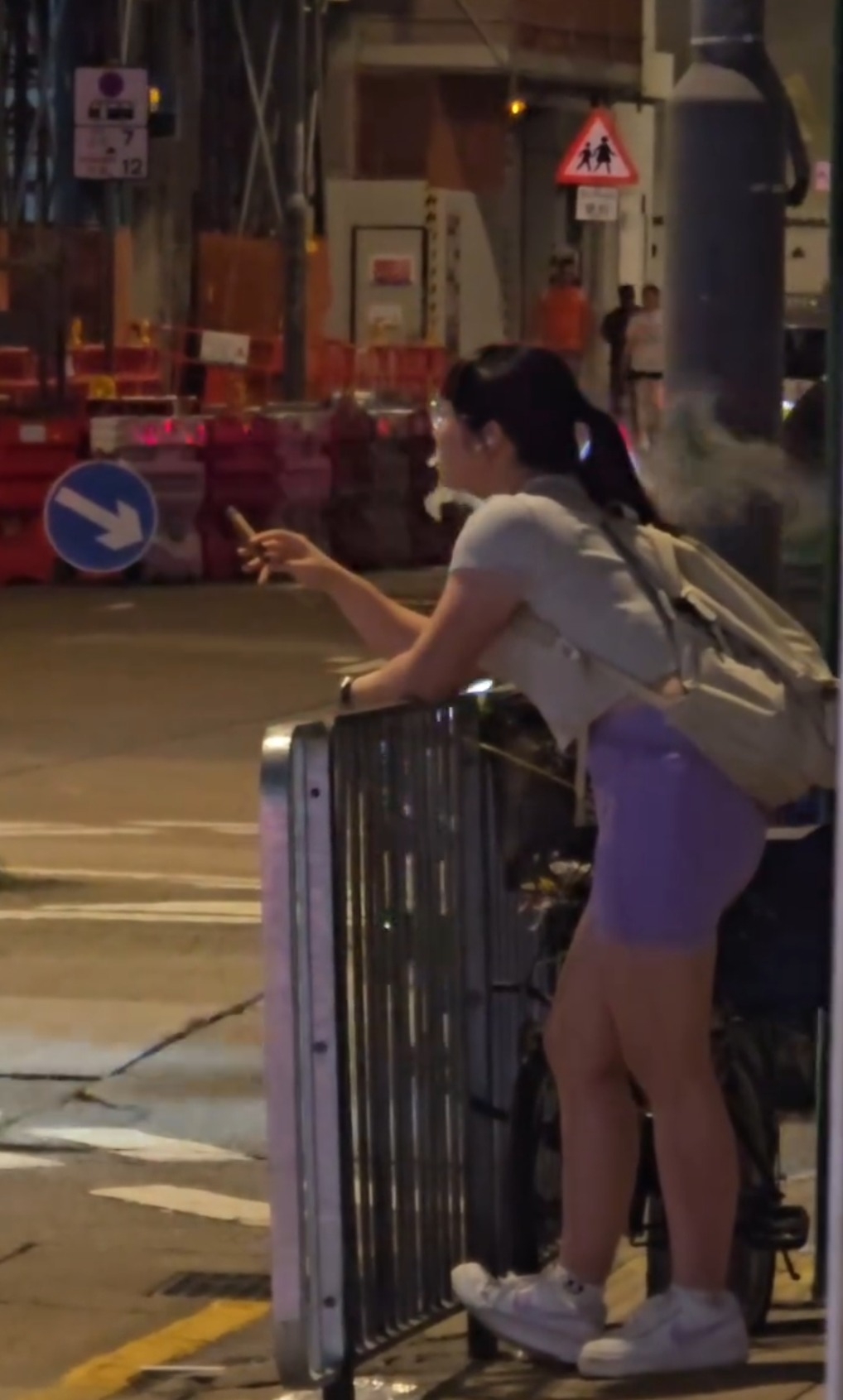 近日社交平台上一段街頭短片引起網民熱烈討論，片中一名年輕女子在夜晚街頭倚靠鐵欄，手持一支雪茄，神態自若，背景是工地圍板與交通指示牌，場景頗具都市感。