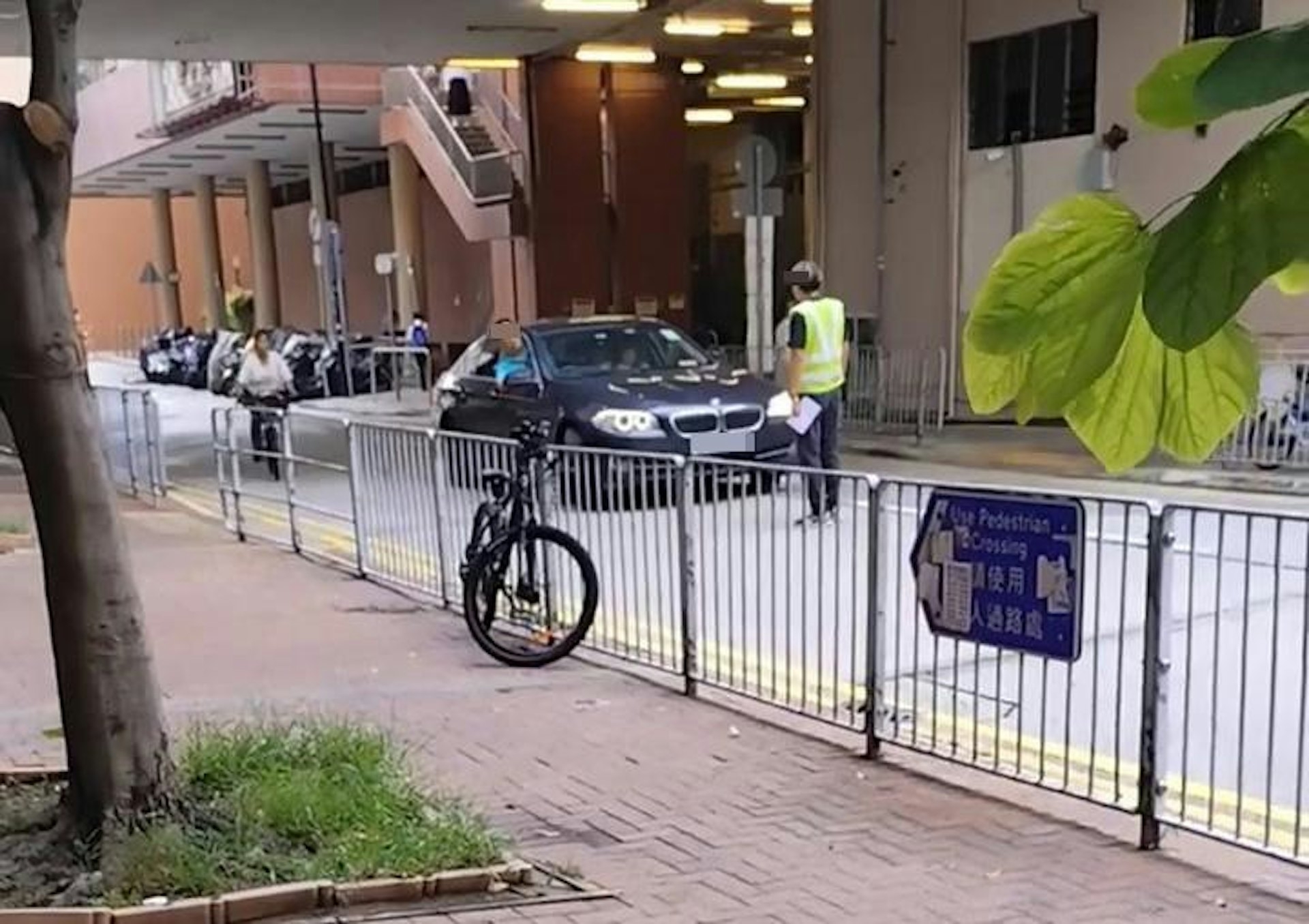寶馬私家車駛入屯門市中心巴士專用區，穿上反光衣的保安站在車頭前方。  