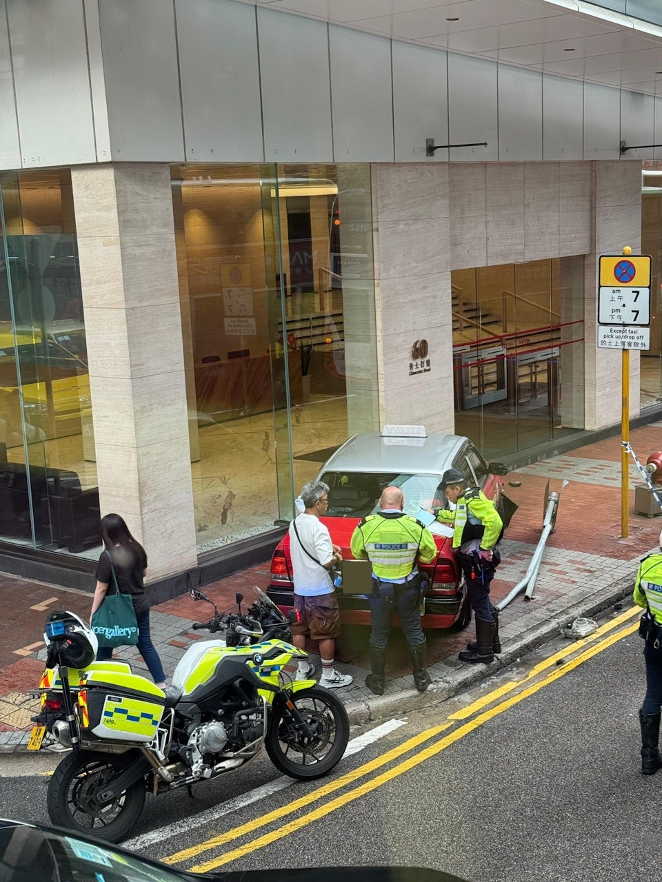 網上圖片可見，事發後涉事的士停在行人路上，一支指示牌被撞毀。（Facebook圖片）