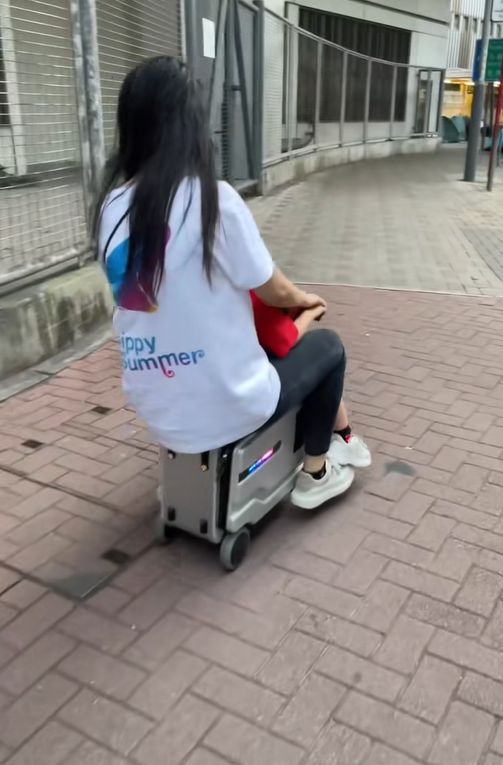女子帶小孩騎電動行李箱周街走