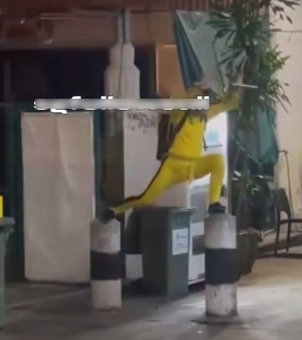 涉事男子於去年9月8日在新加坡芽籠街頭，身穿李小龍標誌性的黃色連身運動衣，站在兩個石躉上揮舞雙節棍。（網上圖片）