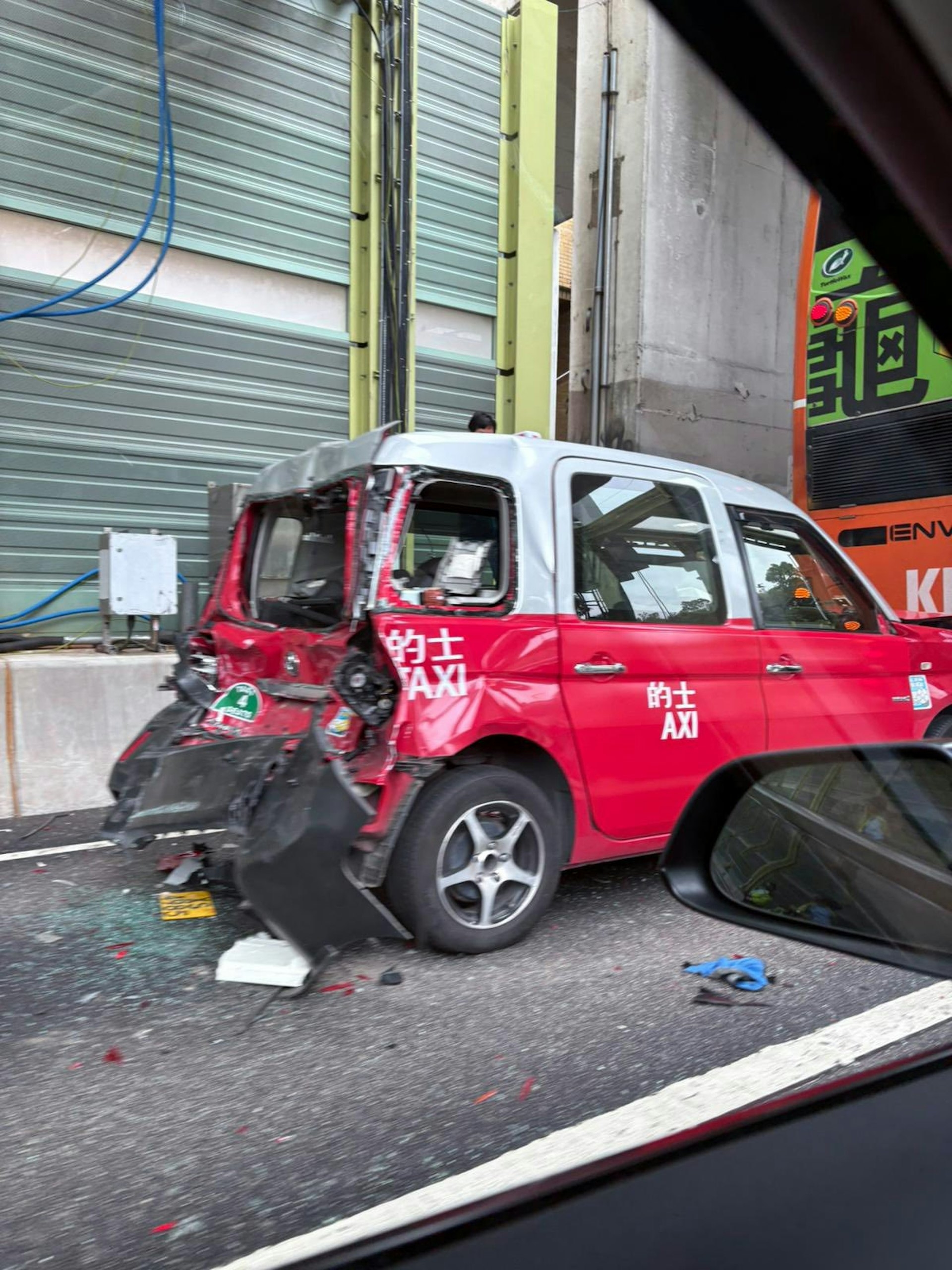 的士被夾在貨車與巴士之間，車尾明顯凹陷。