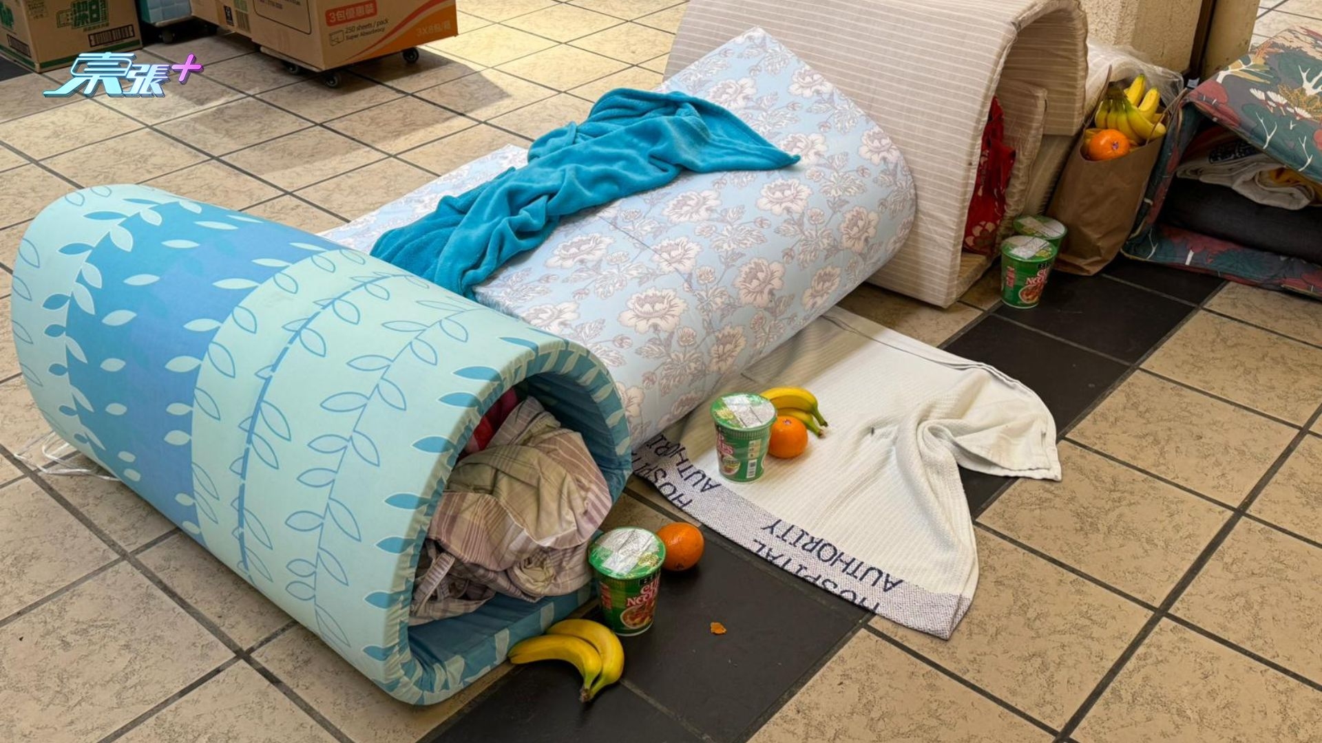 《東張+》記者現場所見，店舖門口擺放多張床褥，相信是昨晚無法返家的居民臨時歇息之處。附近街坊自發組成支援網絡，不斷送來紙巾、生果、食物及食水等必需品。