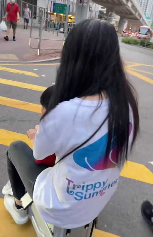 女子帶小孩騎電動行李箱周街走