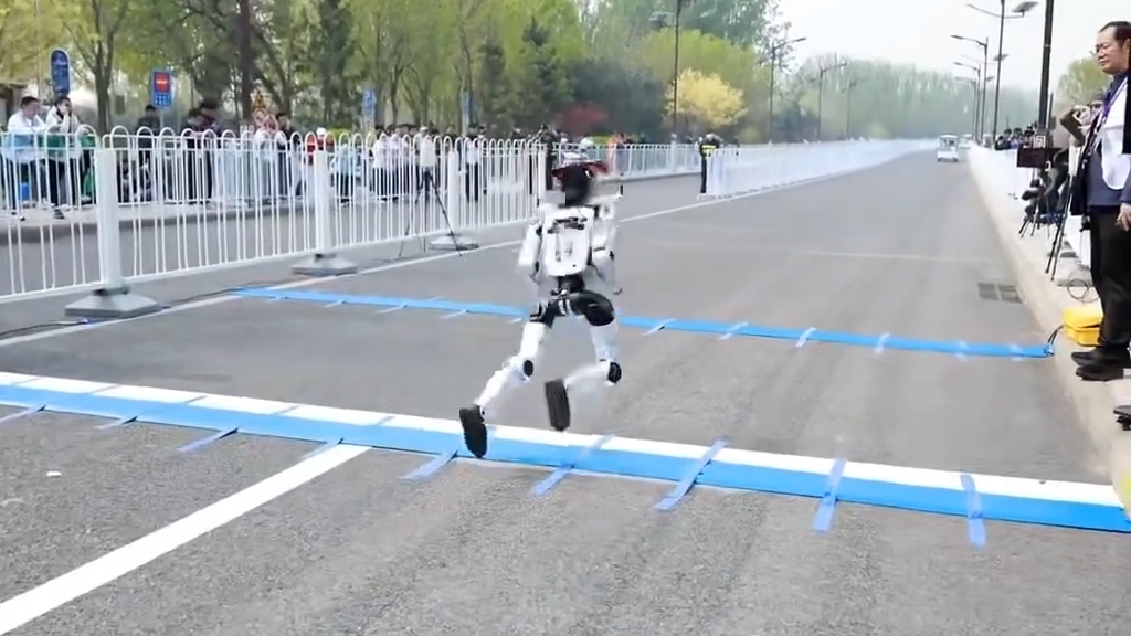 涉事機械人被一條藍白相間的起跑線絆倒，隨後摔倒在地，手臂部位瞬間脫離飛開，不少零件散落一地。（網上影片截圖）