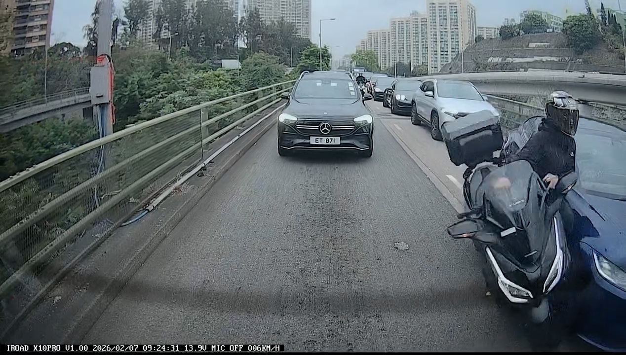 一輛電單車「攝車隙」在兩線中間駛至，此時左邊行車線一輛深藍色Tesla私家車突然向右扭軚切線，電單車鐵騎士閃避不及，撞上Tesla私家車發生碰撞，人車翻倒跌在地上。（Facebook影片截圖／車cam L（香港群組）／KM Pang）