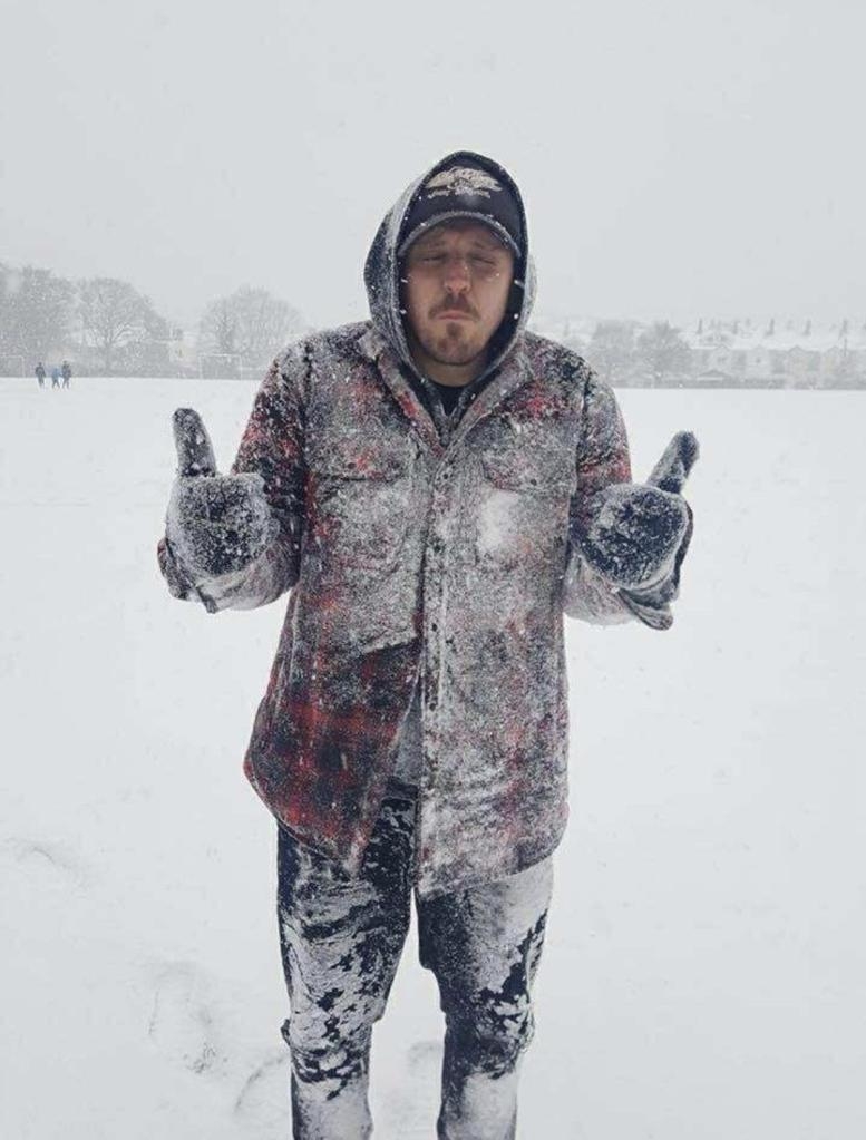 Mal Nash stands in a snowy field covered in snow, giving two thumbs up.