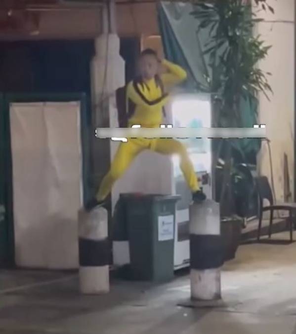 涉事男子於去年9月8日在新加坡芽籠街頭，身穿李小龍標誌性的黃色連身運動衣，站在兩個石躉上揮舞雙節棍。（網上圖片）