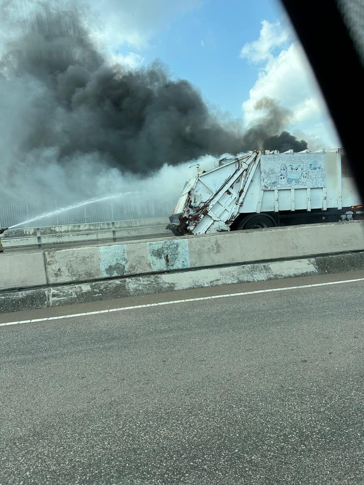起火垃圾車駕駛室火光熊熊，連同後方的鐵籠亦有著火，冒出濃煙，消防員則正在進行灌救。（Facebook圖片／車cam L（香港群組）／Bosco Chu）