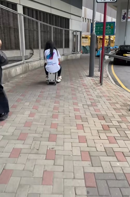 女子帶小孩騎電動行李箱周街走
