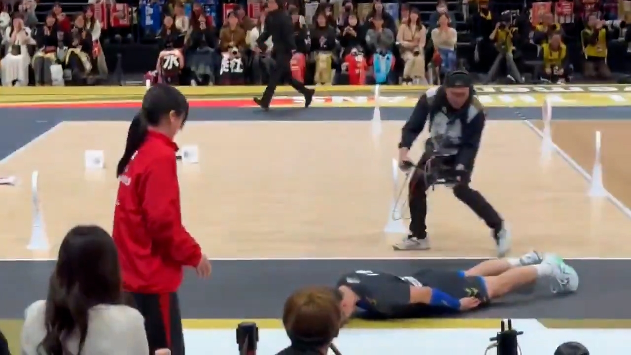 西田有志迅速跑向這名女性工作人員，接着使出排球場上專業救球的「魚躍滑行」動作，整個人從頭到腳完全貼合在地面上，滑行至女性工作人員身前。（X影片截圖／@ojin12049290）