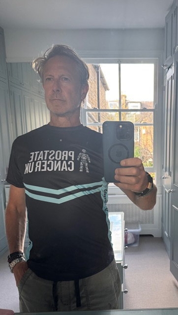 A man taking a mirror selfie, wearing a black shirt that reads 