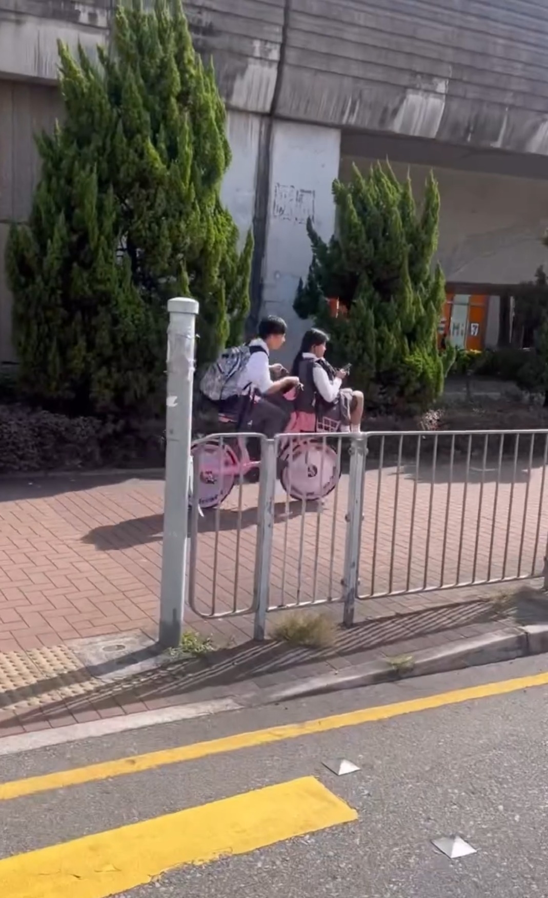 近日社交平台流傳一段短片，顯示兩名身穿校服的中學生使用共享單車過馬路，其中一人騎車，另一人則坐在單車前方的物品籃內，場面引起網民熱烈討論 (網上截圖)