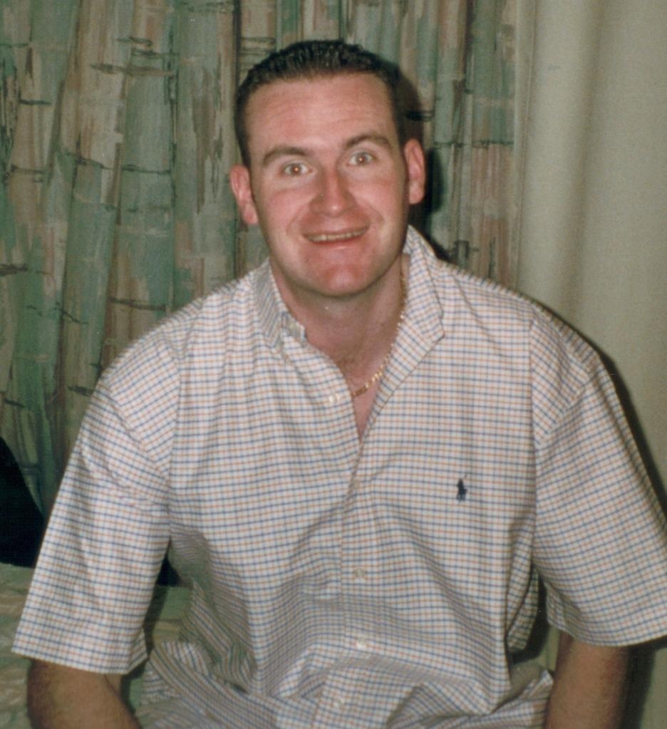 John Granahan, aged 25, wearing a plaid shirt and smiling at the camera.