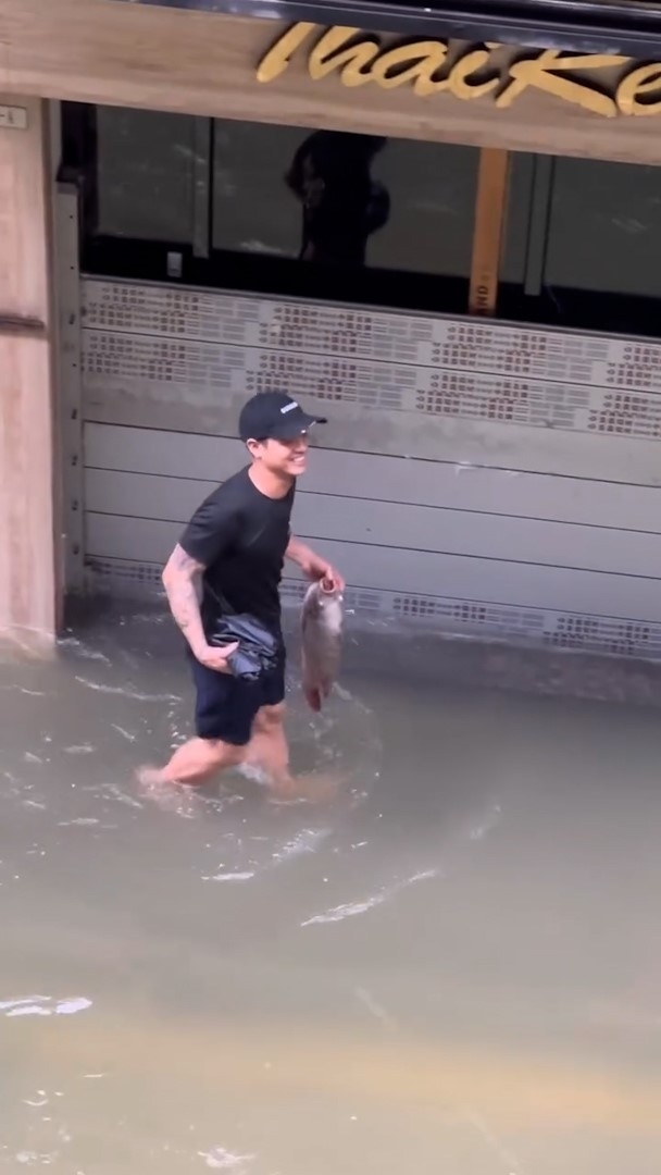 在澳門水浸的街道上，有民眾在嘗試捉魚，以及成功將新鮮魚撿走。（Threads影片截圖／apmacau）