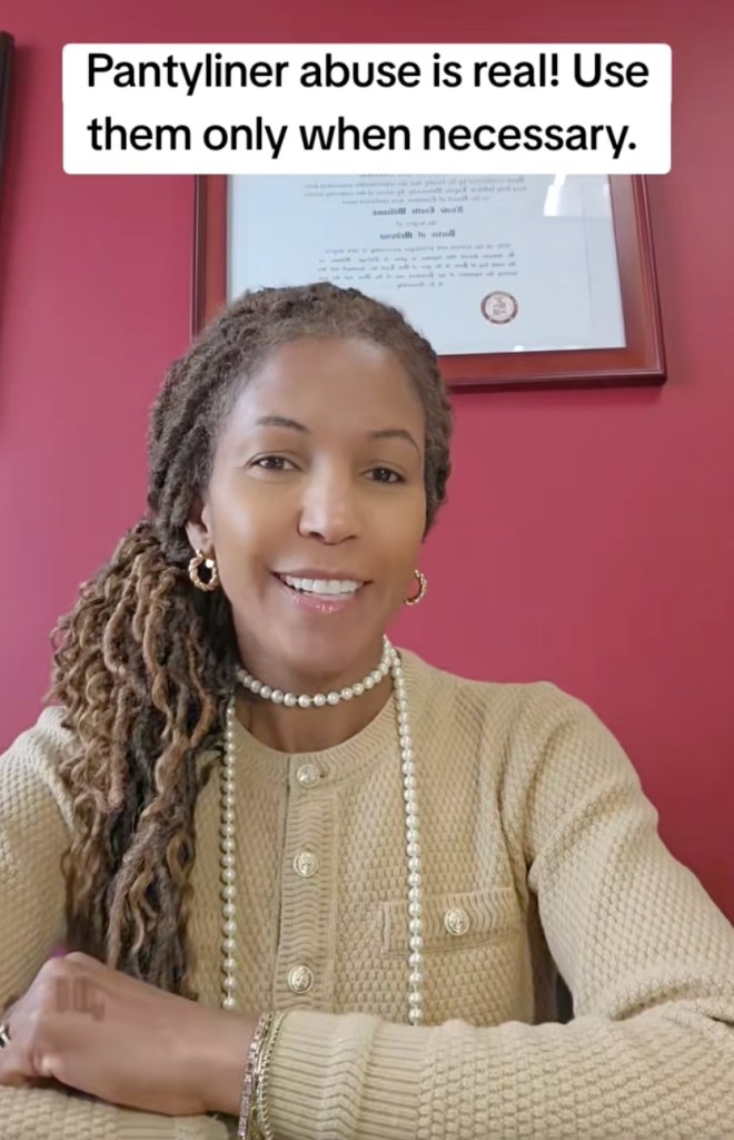 A woman with dreadlocks and wearing pearls smiles at the camera, with text above her head reading, 