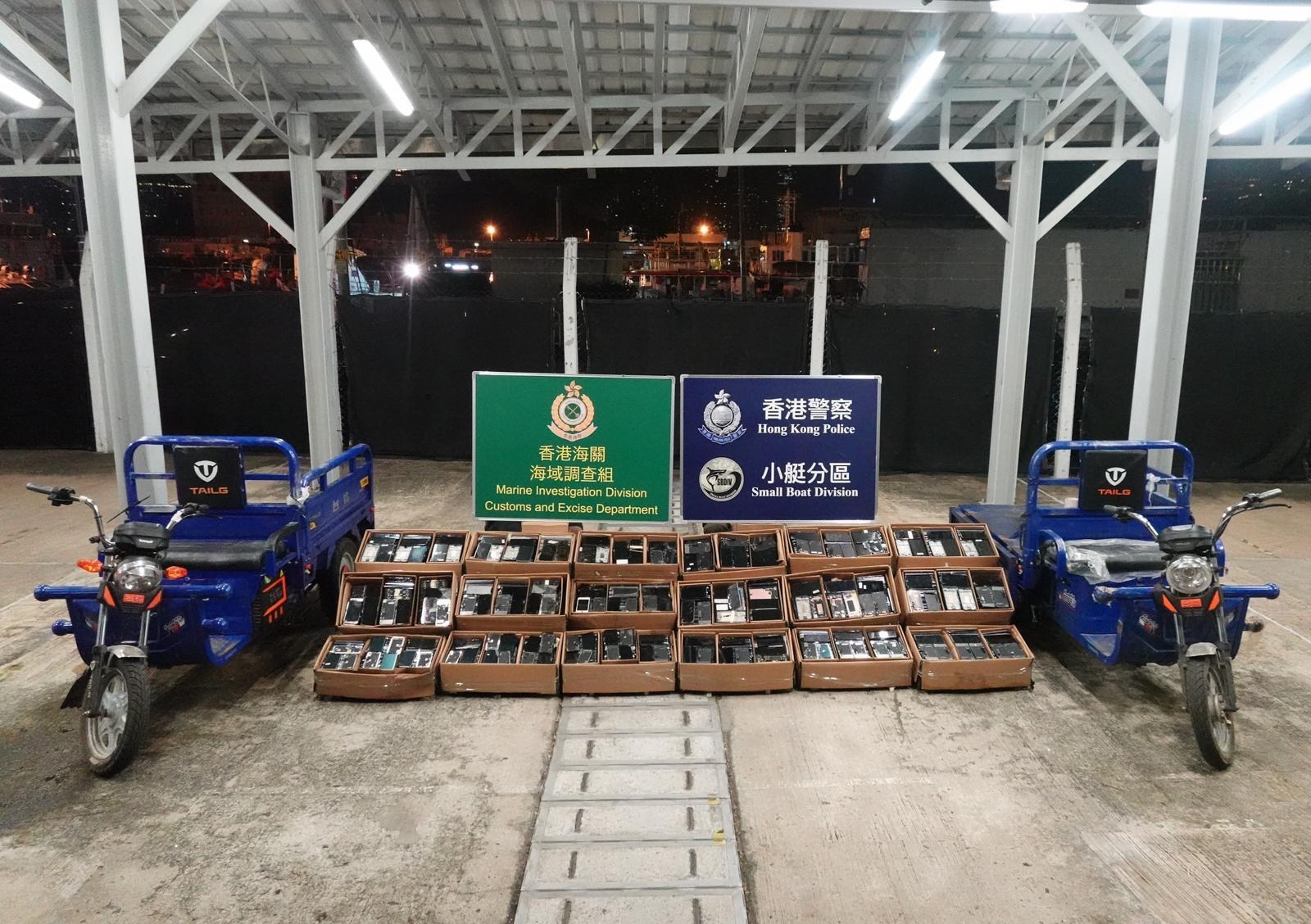 人員在現場岸邊，共檢獲約5600件不同品牌的手提電話零件，估計市值約45萬元，並扣查涉案電動三輪車。（警方圖片）