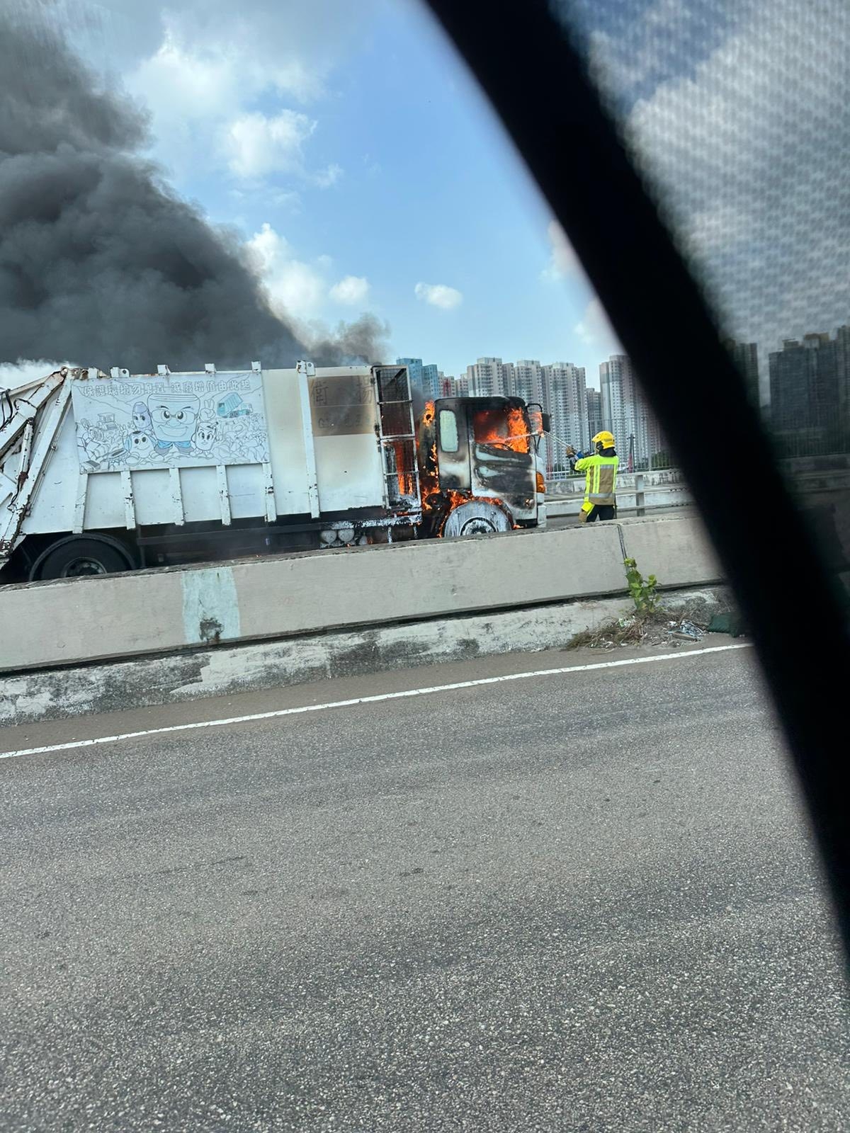起火垃圾車駕駛室火光熊熊，連同後方的鐵籠亦有著火，冒出濃煙，消防員則正在進行灌救。（Facebook圖片／車cam L（香港群組）／Bosco Chu）