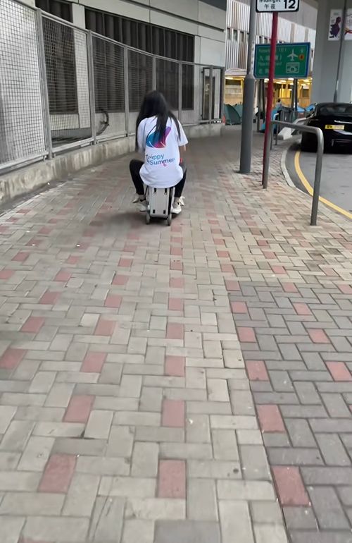 女子帶小孩騎電動行李箱周街走