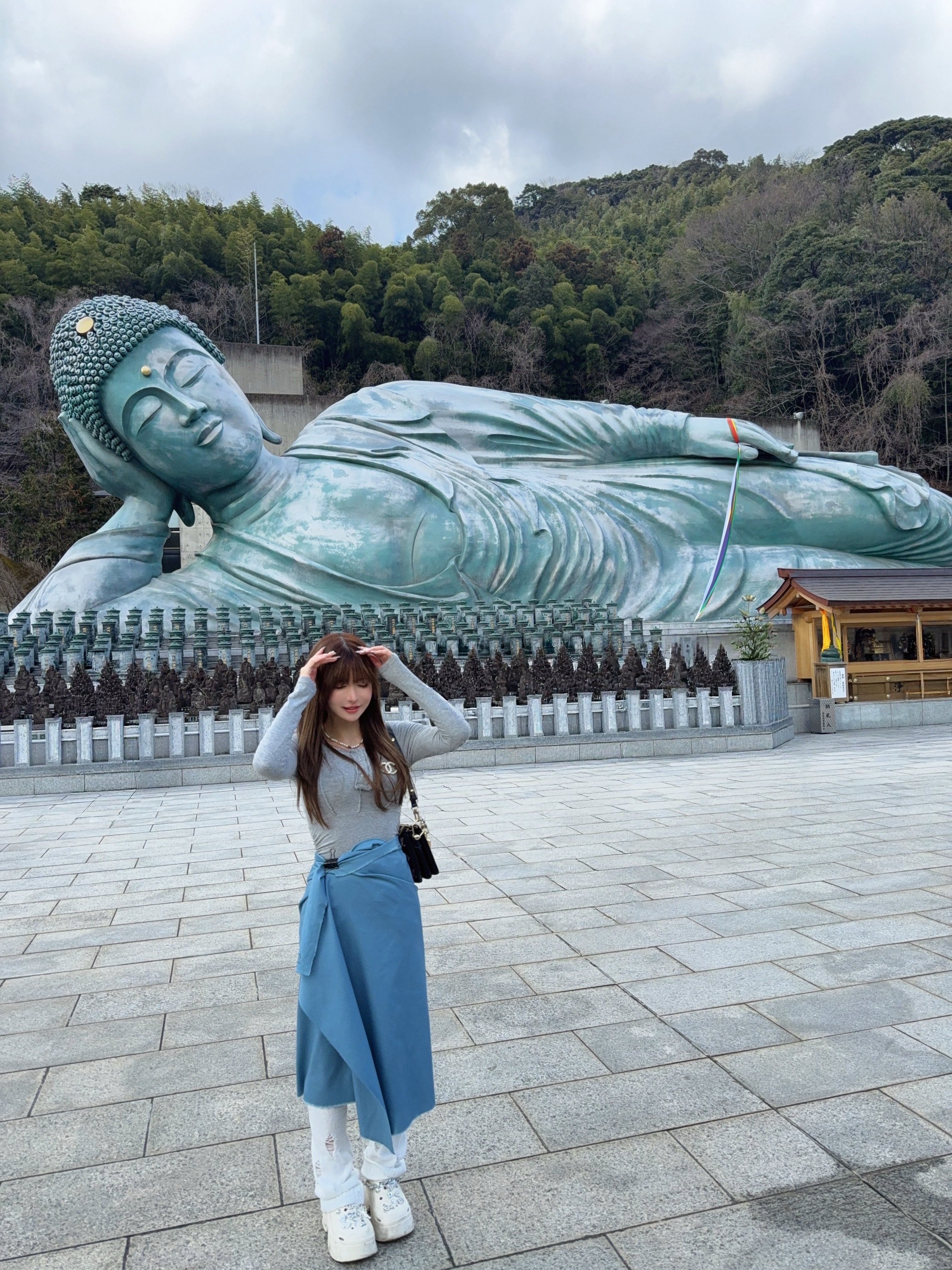 從Hotaru分享的照片可見，她站在釋迦涅槃像前，穿着一件灰色長袖上衣，搭配白色泡泡襪，腰際上圍著稍顯突兀的深藍色布。（X圖片／@hhh_Load）
