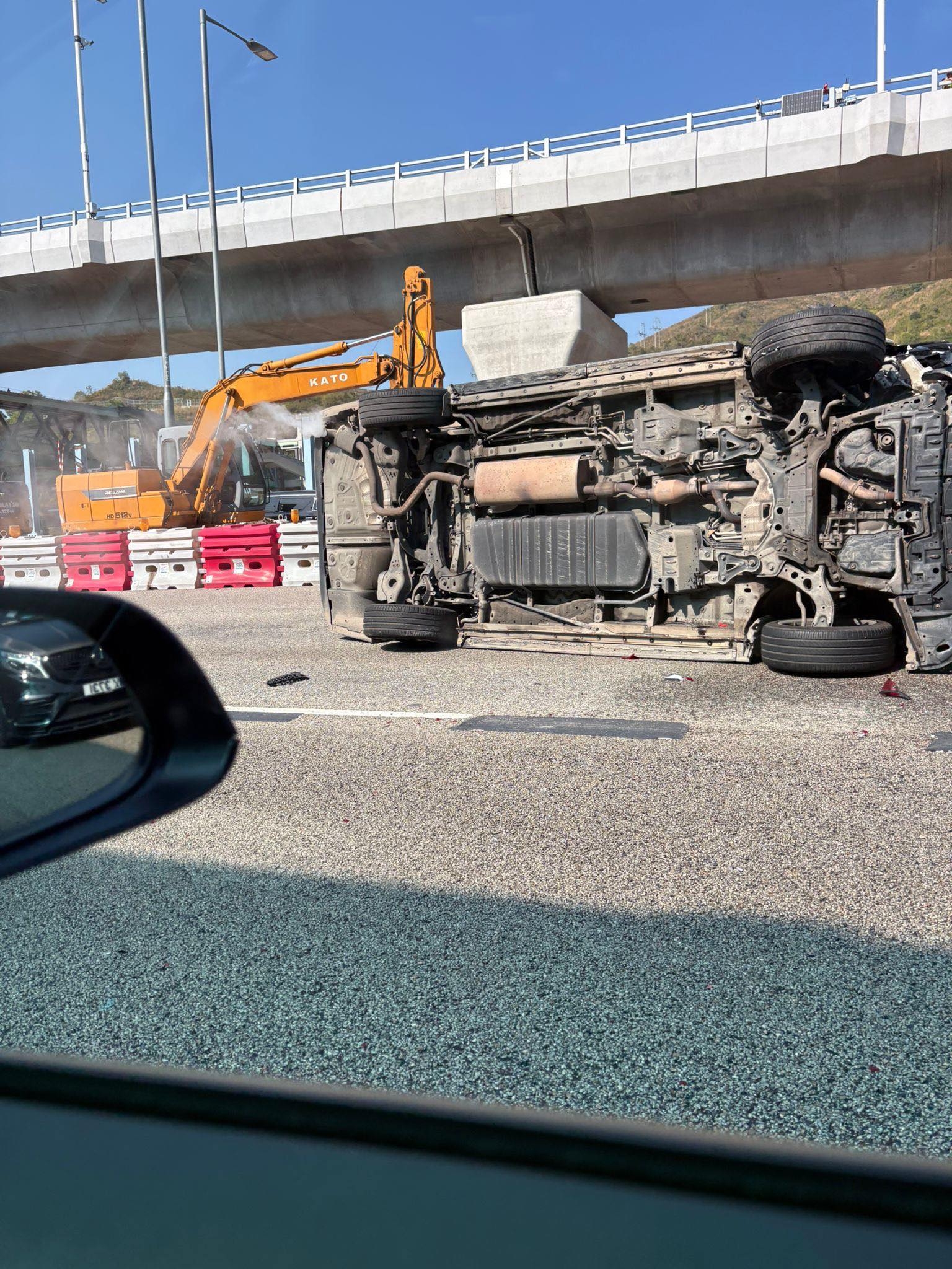 涉事黑色私家車向左翻側，橫亘路中，車尾冒白煙，車頭嚴重損毀，零件碎片散落一地。（Facebook圖片／車cam L（香港群組）／Bosco Chu）