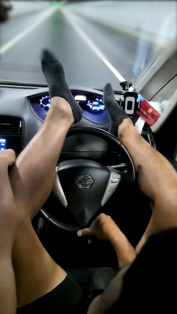 一名男子駕車駛經一條隧道時，將雙腳放在軚盤上方，並僅用一隻手扶著軚盤。（Facebook影片截圖／車cam L（香港群組）／Hui Lam）