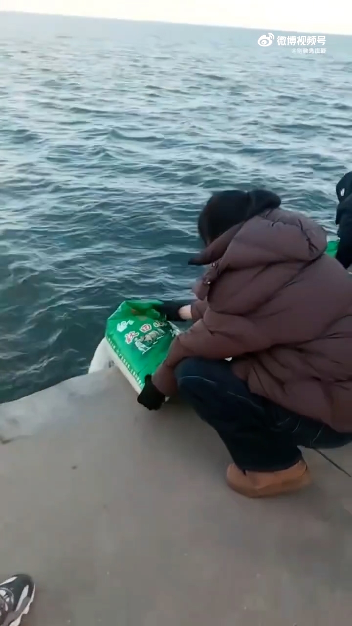 在事發現場，數名中老年人將多袋已開封的大米傾倒入海。（網上影片截圖）