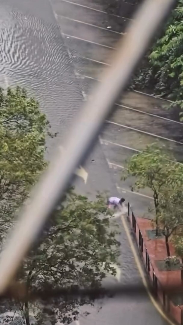 在澳門水浸的街道上，有民眾在嘗試捉魚，以及成功將新鮮魚撿走。（Threads影片截圖／chontou0724）