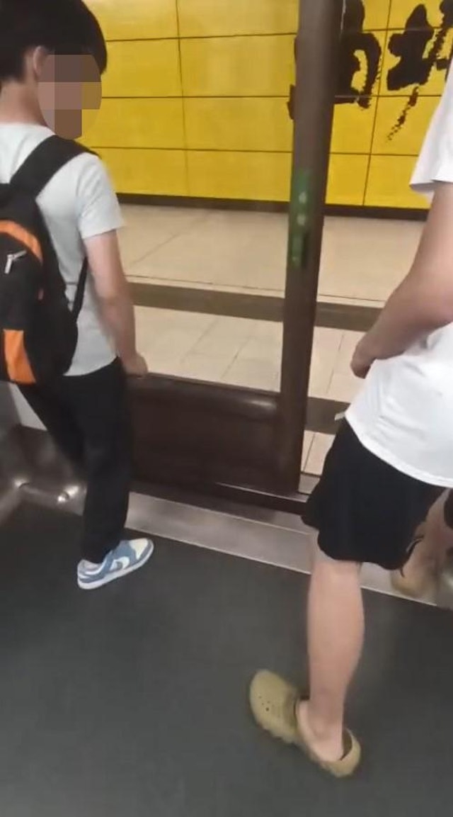 月台幕門關上時，列車門被兩名男子用腳擋着未能關上。（網上片段截圖）