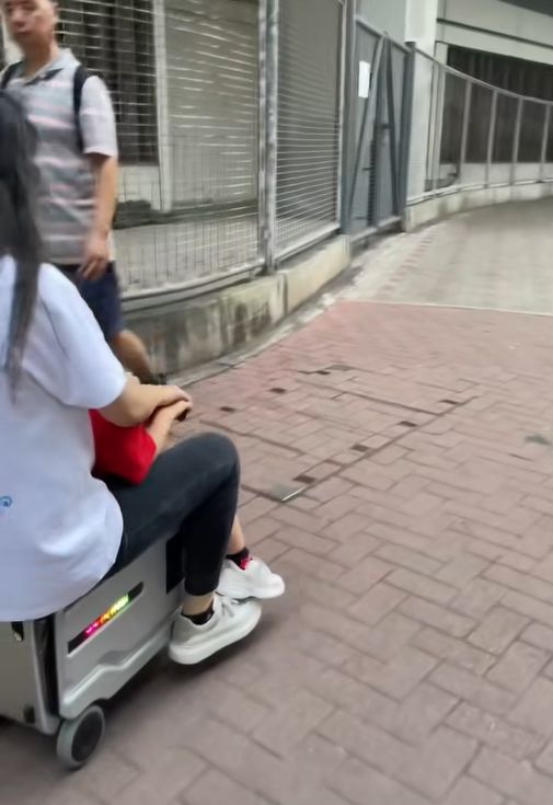 女子帶小孩騎電動行李箱周街走