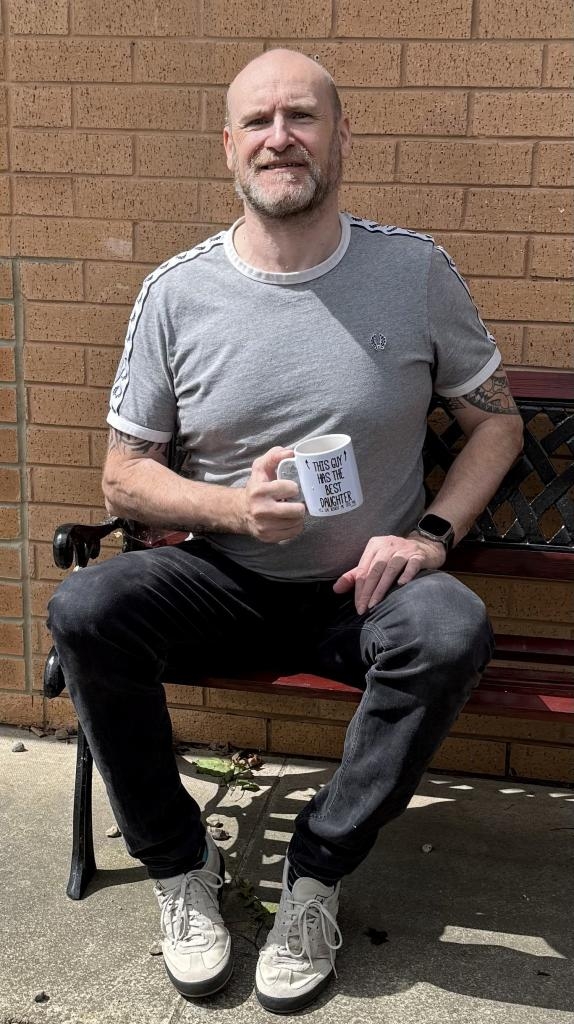 John Granahan, a man who was diagnosed with Parkinson's aged 20, holds a mug saying 