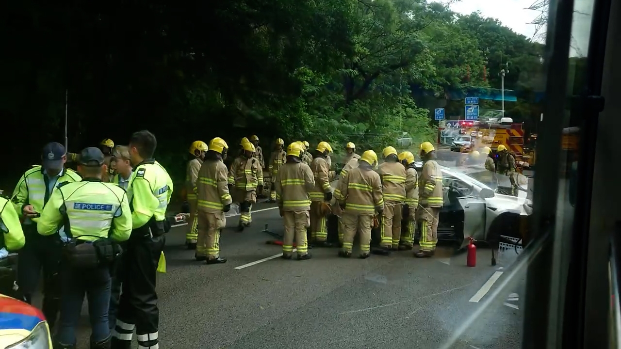 大批消防員與警員到場，隧道職員亦在場協助封路處理。涉事Tesla私家車車頭全毀，橫亙慢線和中線之間。（Facebook影片截圖／車cam L（香港群組）／Colin Leung）