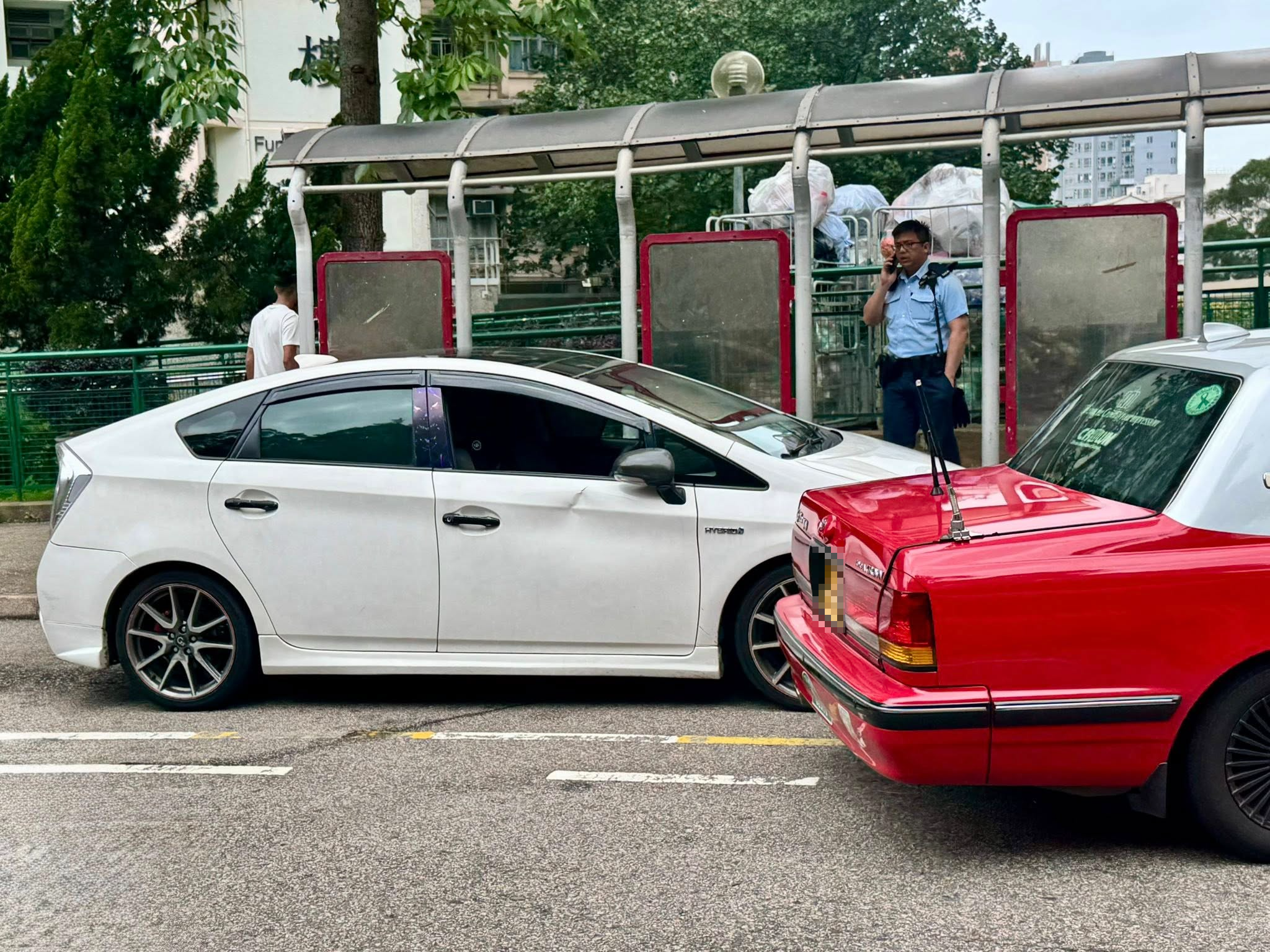 現場一輛白色私家車和一輛的士停在澤蔭樓對開的士站，的士「斜插」在私家車前方，白色私家車司機位的車門凹陷。（Facebook圖片／馬路的事 (即時交通資訊台)／Him Tang）