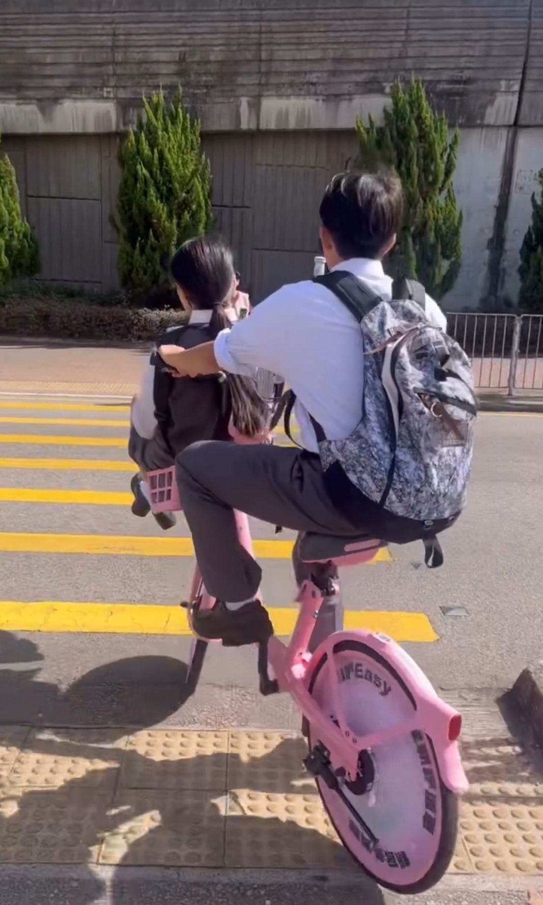 近日社交平台流傳一段短片，顯示兩名身穿校服的中學生使用共享單車過馬路，其中一人騎車，另一人則坐在單車前方的物品籃內，場面引起網民熱烈討論 (網上截圖)