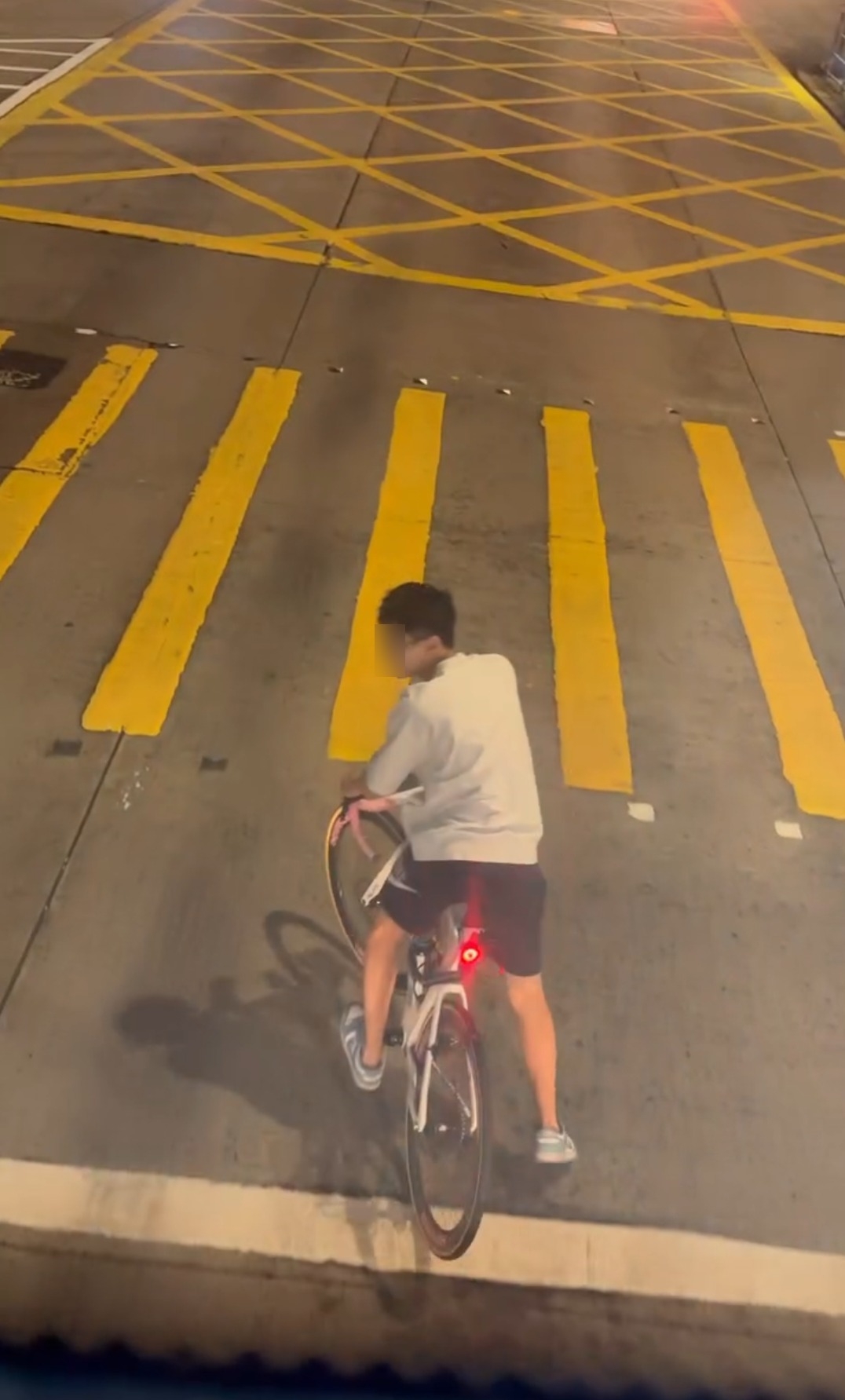 畫面中，一名身穿白衣的少年於馬路上踩單車，停在紅綠燈白線前，面對逼近的巴士仍未讓路，更面帶笑容回望，疑似與友人聊天。