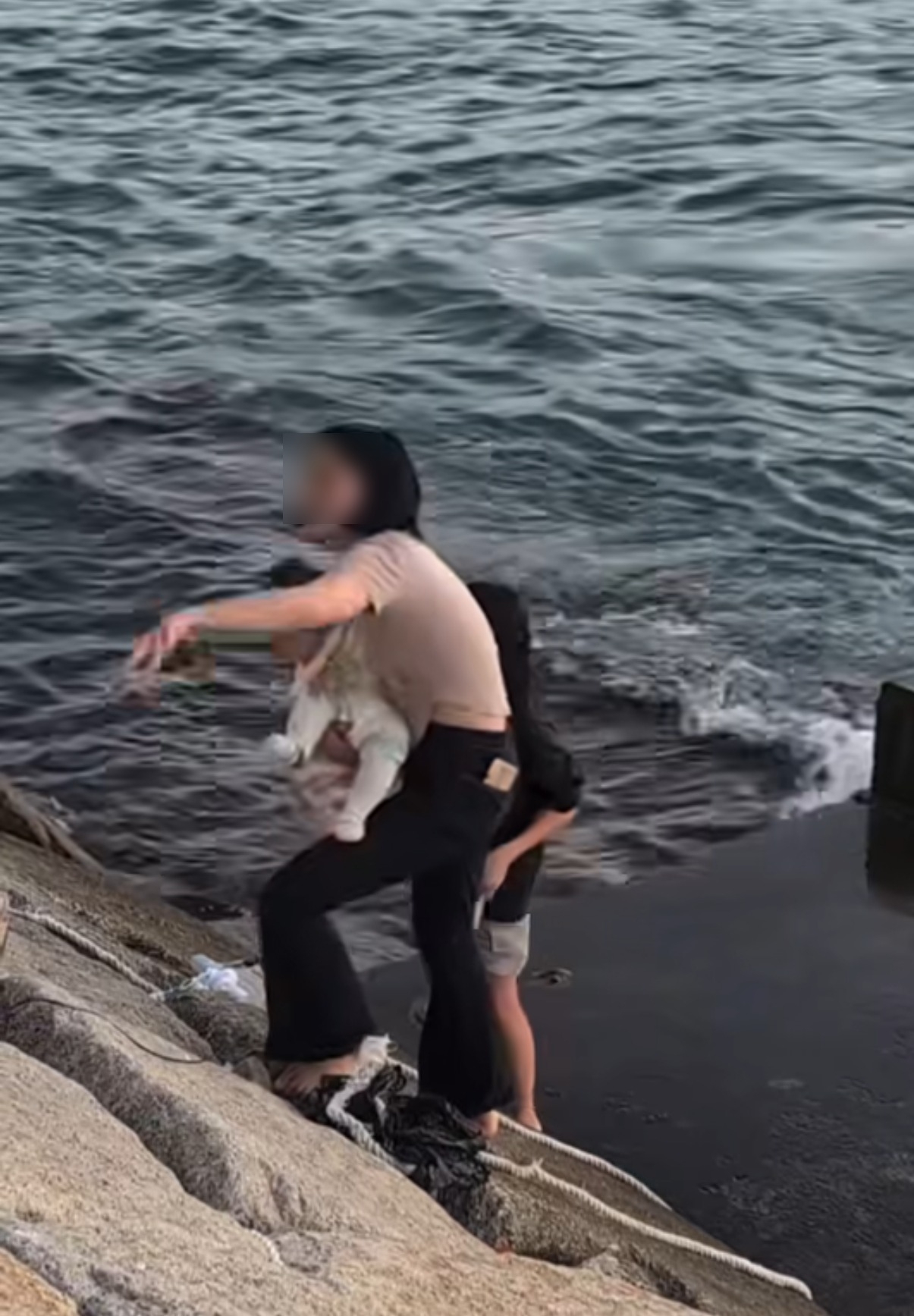 根據影片顯示，涉事位置為啟德海濱一段石屎斜坡下的小平台，平台僅略高於海水，周遭亦未見防護欄或救生設備。