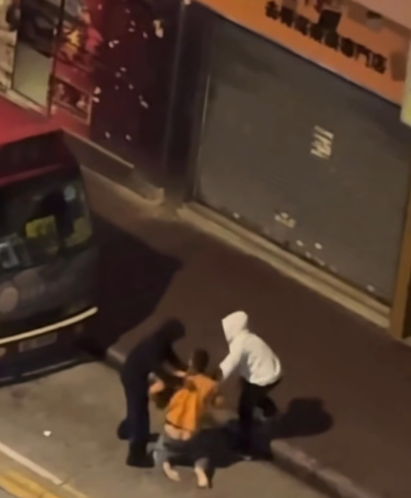 一名身穿橙色上衣的男子遭兩名男子襲擊，對方企圖搶走其手袋，期間更出手毆打。