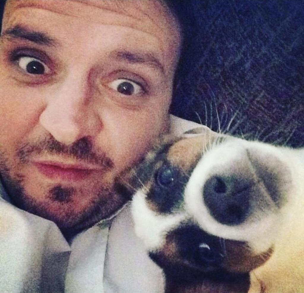 Mal Nash lying on a couch with a small white, brown, and black dog.